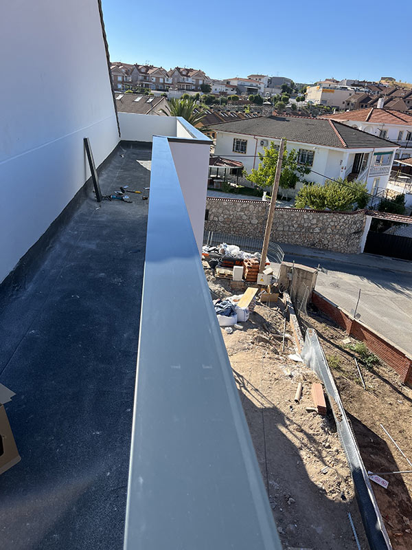 Instalación de cubremuros de aluminio sobre tejado en construcción